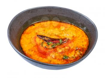 Indian cuisine - portion of yellow Dal Tadka (spicy smooth and creamy chowder from lentils with curry) in black bowl isolated on white background