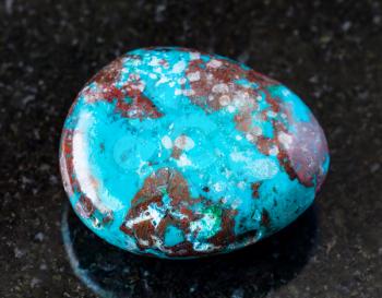 closeup of sample of natural mineral from geological collection - polished Chrysocolla with Cuprite rock on black granite background
