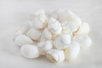 many organic silkworm cocoons for facial skin care on white silk fabric