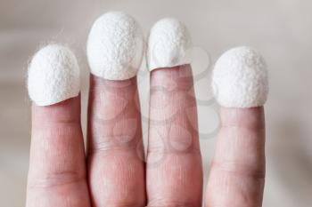 natural silk cocoons for facial skin care wear on tips of fingers close up
