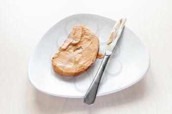 above view of toast with creamy peanut butter and knife on plate on table