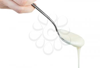 side view of natural organic white honey pouring from steel spoon isolated on white background