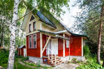 one-storey wooden summerhouse with attic in Russia in summer