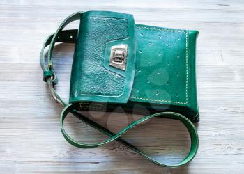 top view of handcrafted green leather tablet bag on gray wooden table