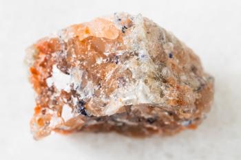 closeup of sample of natural mineral from geological collection - unpolished red Rock Salt (Halite) on white marble background from Perm Krai, Russia