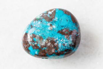 closeup of sample of natural mineral from geological collection - polished Chrysocolla with Cuprite rock on white marble background