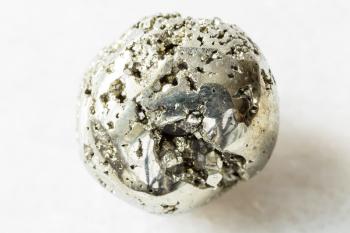 closeup of sample of natural mineral from geological collection - tumbled Pyrite (iron pyrite, fool's gold) rock on white marble background from Ancash, Bolognesi, Huallanca, Huanzala Mine in Peru