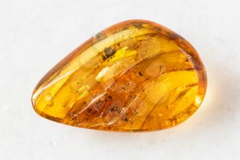 closeup of sample of natural mineral from geological collection - polished Amber gem stone on white marble background from Baltic Sea, Kaliningrad, Russia
