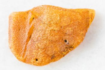 closeup of sample of natural mineral from geological collection - unpeeled nugget of Amber gemstone on white marble background from Baltic Sea, Kaliningrad, Russia