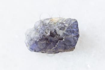 closeup of sample of natural mineral from geological collection - rough Cordierite (Iolite) crystal on white marble background from Madagascar