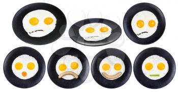 collection of various fried eggs with faces on black plate isolated on white background. Fried eggs like smiling faces