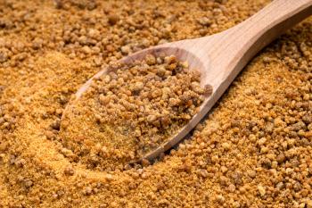 above view of wooden spoon with granulated coconut blossom sugar close up on pile of sugar