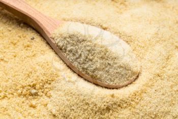 wooden spoon with granulated coconut sugar close up on pile of sugar