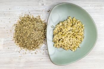 top view of raw freekeh wheat grains and boiled porridge on green plate on wooden table