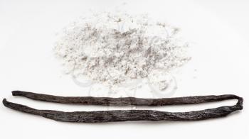 whole vanilla beans and pile of vanilla sugar (sugar powder with ground natural vanilla) close up on white plate