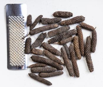 top view of java long pepper with grater close up on gray ceramic plate