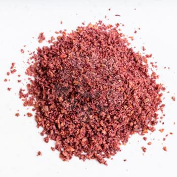 top view of pile of ground sumac spice close up on gray ceramic plate