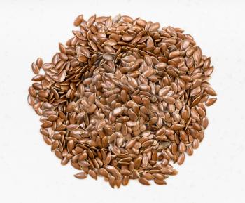 top view of pile of brown flax seeds close up on gray ceramic plate