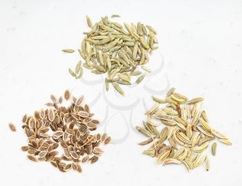 three pinches of anise, dill and fennel seeds on gray ceramic plate