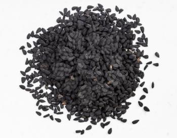 top view of pile of Nigella sativa seeds (black caraway) close up on gray ceramic plate