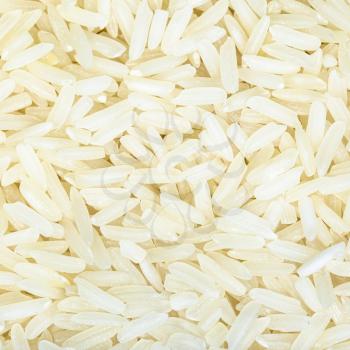 square food background - uncooked polished long-grain jasmine rice close up
