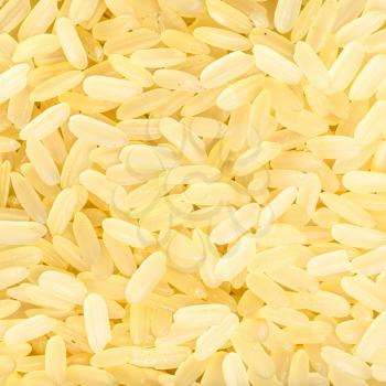 square food background - raw parboiled long-grain rice close up