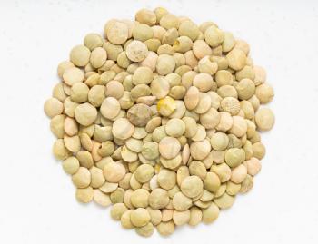 top view of pile of raw whole light green lentils close up on gray ceramic plate
