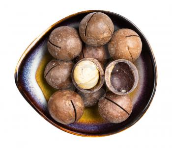 top view of sawn and shelled macadamia nuts in ceramic bowl isolated on white background