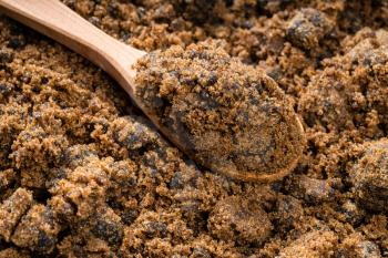 wooden spoon with dark muscovado cane sugar close up on pile of sugar