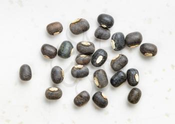 several raw whole black urad beans close up on gray ceramic plate