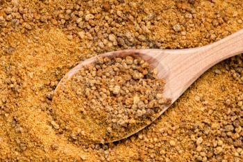top view of wood spoon with granulated coconut blossom sugar close up on pile of sugar