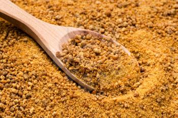 wooden spoon with granulated coconut blossom sugar close up on pile of sugar