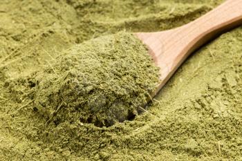above view of wooden spoon with milled stevia rebaudiana herb (natural sugar substitute) close up on pile of sugar