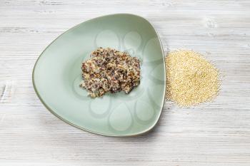 quinoa grains and boiled porridge on green plate on wooden table