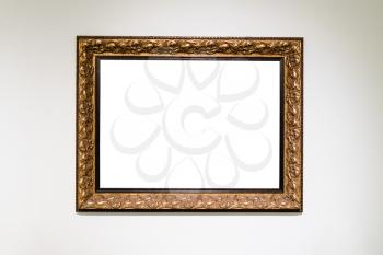 old carved wide bronze picture frame with cutout canvas on white wall