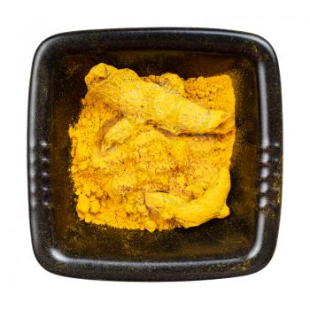 top view of Turmeric (Curcuma) powder and roots in black bowl isolated on white background