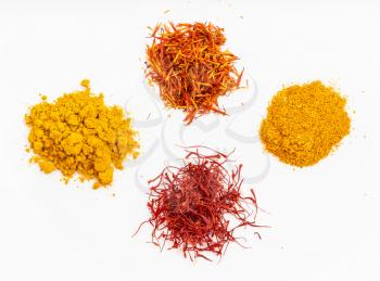 top view of saffron and natural substitutes (crocus threads, turmeric powder, safflower petals, ground tagetes) on white plate