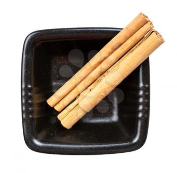 top view of two sticks of alba premium ceylon cinnamon in black bowl isolated on white background