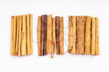 top view of various cinnamon sticks (alba premium ceylon, chinese cassia and continental ceylon cinnamon) on white plate