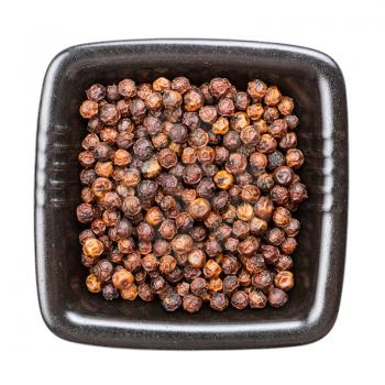 top view of red kampot pepper in black bowl isolated on white backgrouns