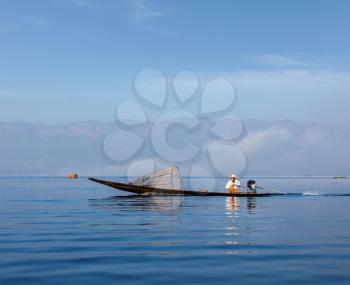 Myanmar travel attraction landmark - Traditional Burmese fisherman with fishing net at Inle lake in speeding motor boat