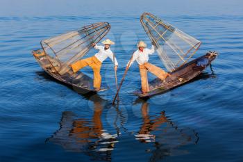 Myanmar travel attraction landmark - Traditional Burmese fishermen balancing with fishing net at Inle lake in Myanmar famous for their distinctive one legged rowing style