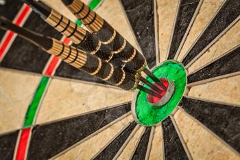 Success hitting target aim goal achievement concept background - three darts in bull's eye close up