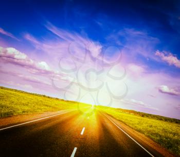 Vintage retro effect filtered hipster style image of travel concept background - road in blooming spring meadow on sunset