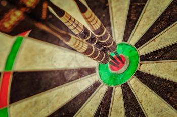 Vintage retro effect filtered hipster style image of - Success hitting target aim goal achievement concept background - three darts in bull's eye close up