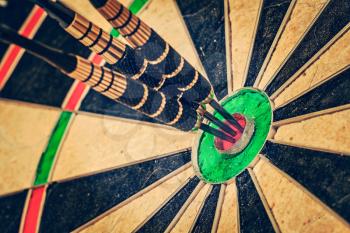Vintage retro effect filtered hipster style image of  - Success hitting target aim goal achievement concept background - three darts in bull's eye close up