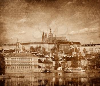 View of Charles bridge over Vltava river and Gradchany (Prague Castle) and St. Vitus Cathedral vintage sepia toned  with grunge texture overlaid