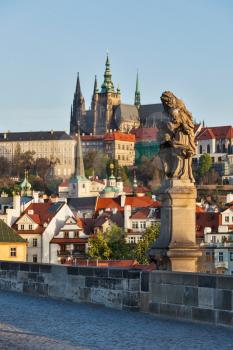 Statue on Charles Brigde with St. Vitus Cathedral in background in Prague