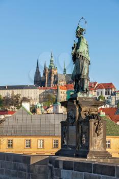 John of Nepomuk or John Nepomucene national saint of the Czech Republic statue on Charles Brigde at the site where the saint was thrown into Vltava with St. Vitus Cathedral in background in Prague