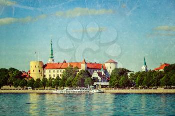 Vintage retro hipster style travel image of 
View of Riga Castle over Daugava river with grunge texture overlaid. Riga, Latvia